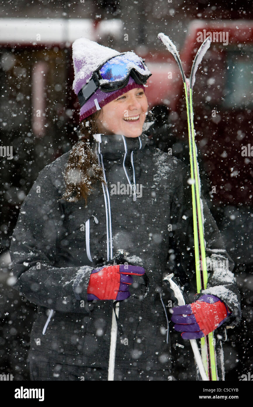 Smiling young woman in ski attire on a snowy day Stock Photo
