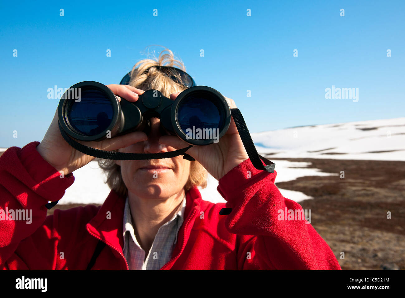 Close-up of a female birdwatcher with binoculars against blue sky Stock Photo