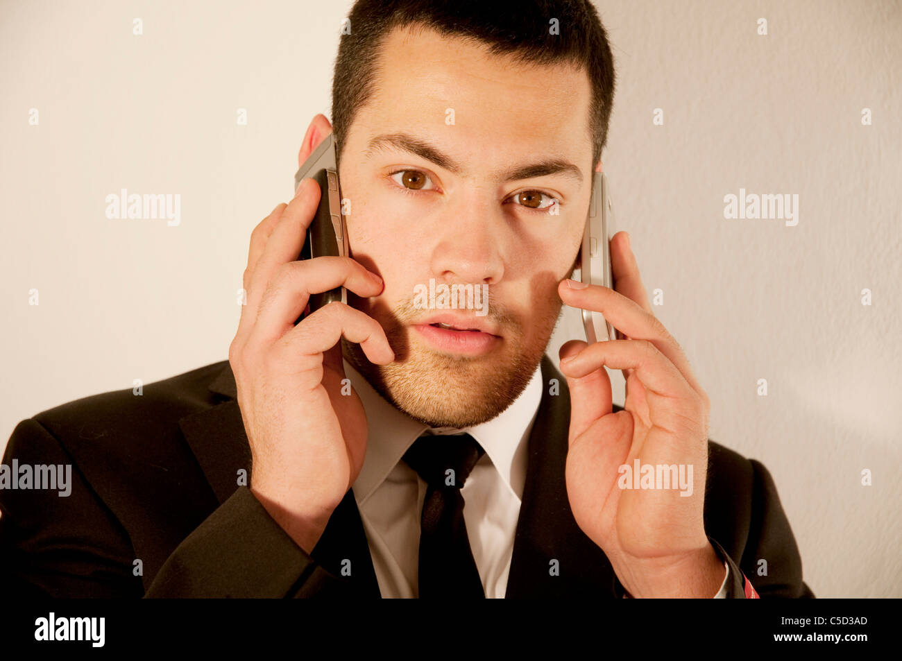 Young man using two mobiles phones. Stock Photo