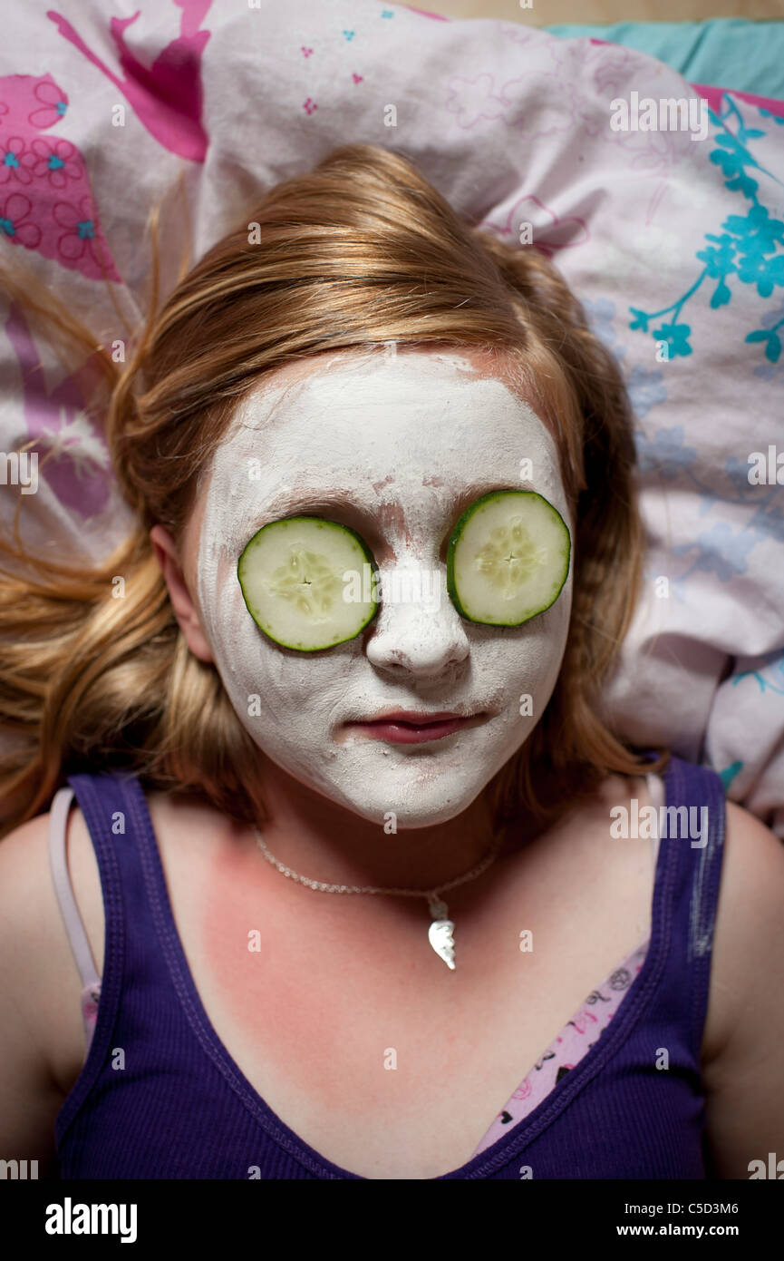 a young teenage girl with facepack and cucumber slices on her eyes