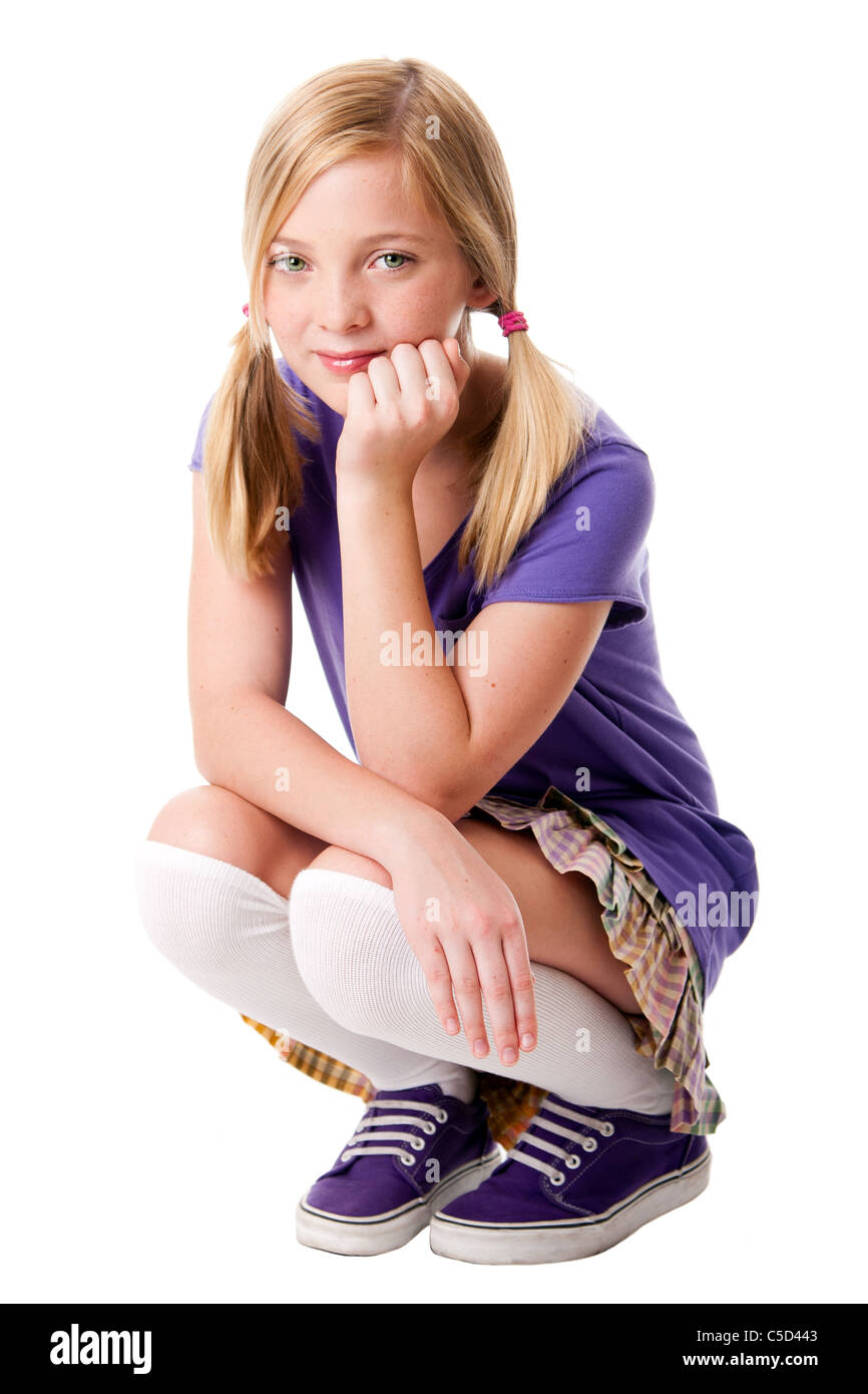 Beautiful happy teenage girl sitting squatted wearing knee socks, purple sporty shoes, shirt and colorful skirt. Stock Photo