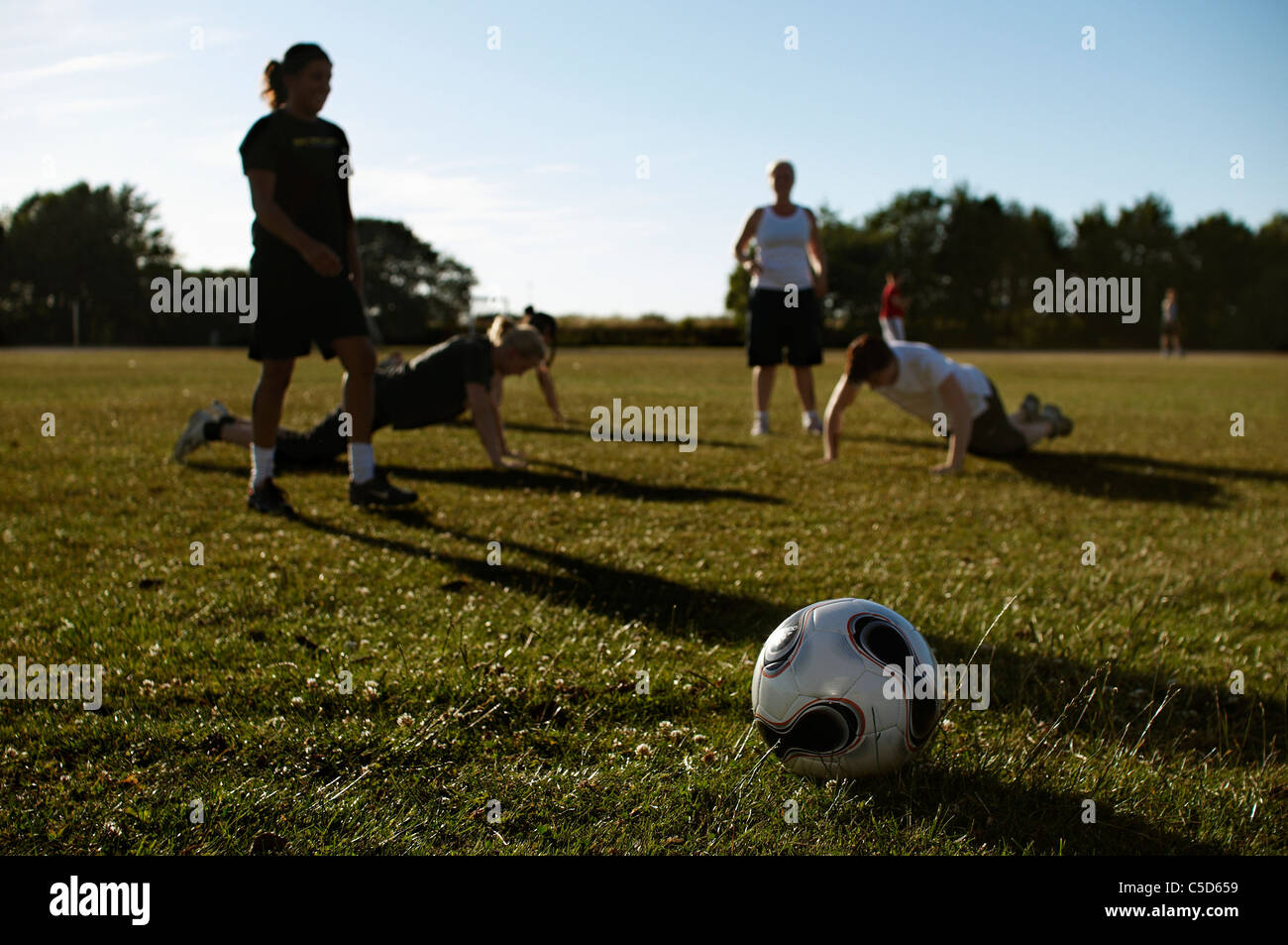 Female players on the grass with soccer ball in the foreground Stock Photo