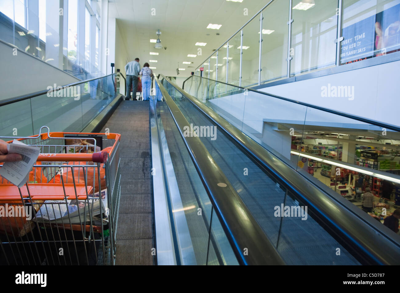 A Sainsbury's shopping trolley going up a travelator at a Sainsbury store. The receipt for food purchased is also in view. UK. Stock Photo