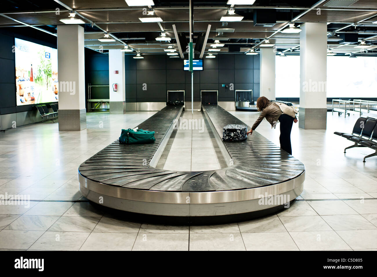 Woman collecting luggage from airport baggage collection isolated and