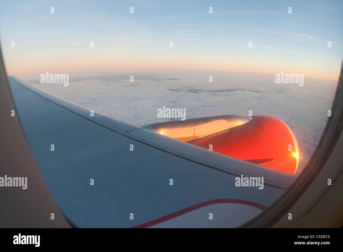 View through an aircraft window flying above clouds. Stock Photo