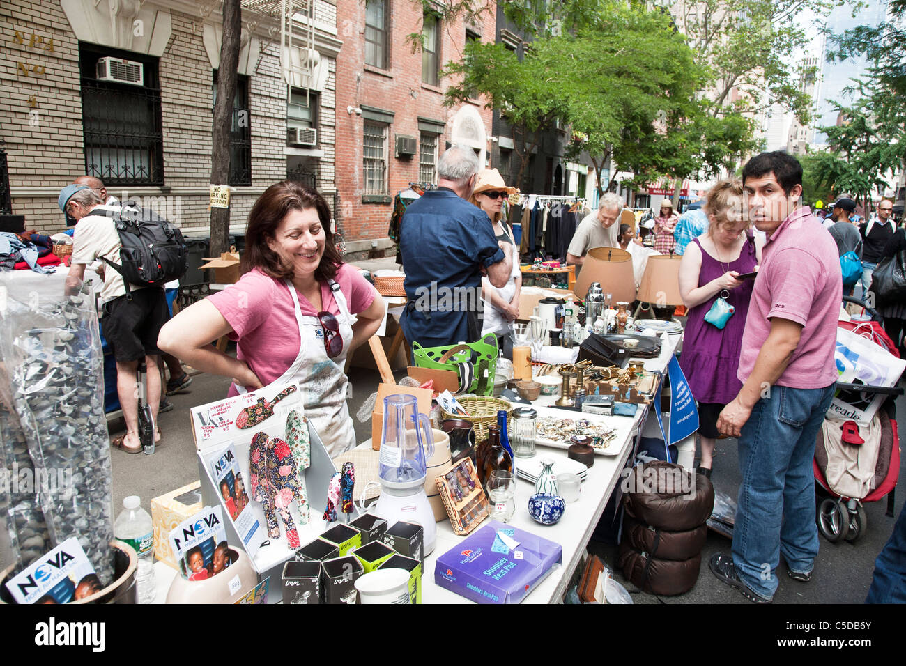 people cluster around tables strewn with treasures & tchotchkes at west 44th street annual flea market & garage sale Manhattan Stock Photo