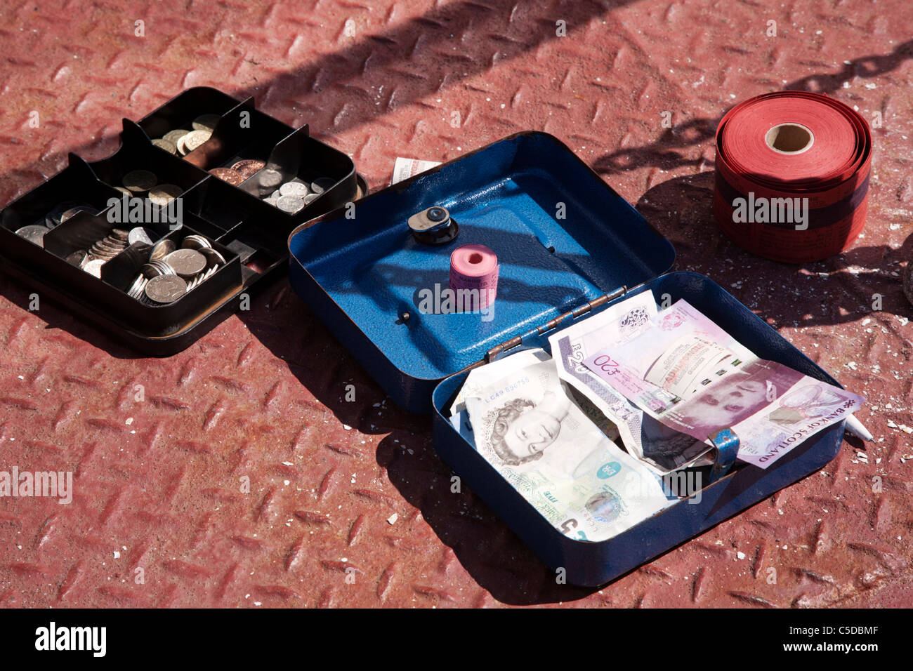 A cash box with takings and tickets on a painted steel floor. Stock Photo