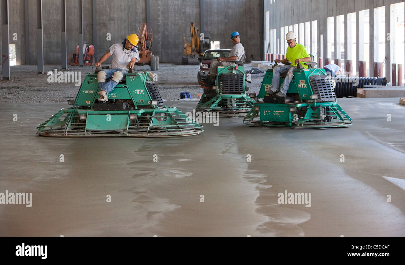 Cement Polishers Riding Power Trowels over freshly poured concrete can smooth the surface to a glass-like finish! Stock Photo