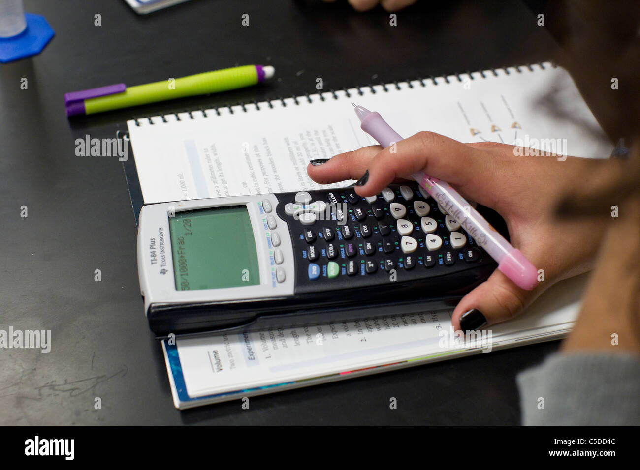 Female student  with dark nail polish,uses graphing calculator over notebook pad during class at her high school in South Texas Stock Photo