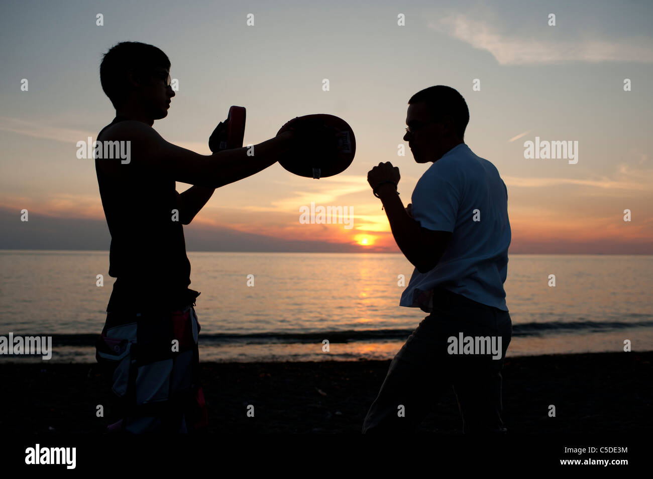 silhouette of Two men sparring shadow boxing at sunset UK Stock Photo