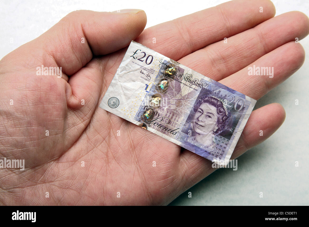 Hand holding shrunken twenty pound note. Stock Photo