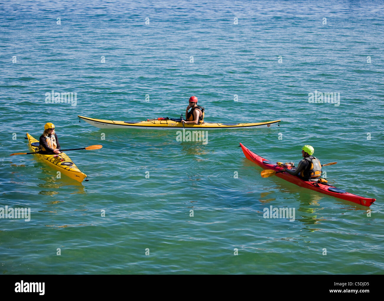 Three kayakers rest on calm water Stock Photo