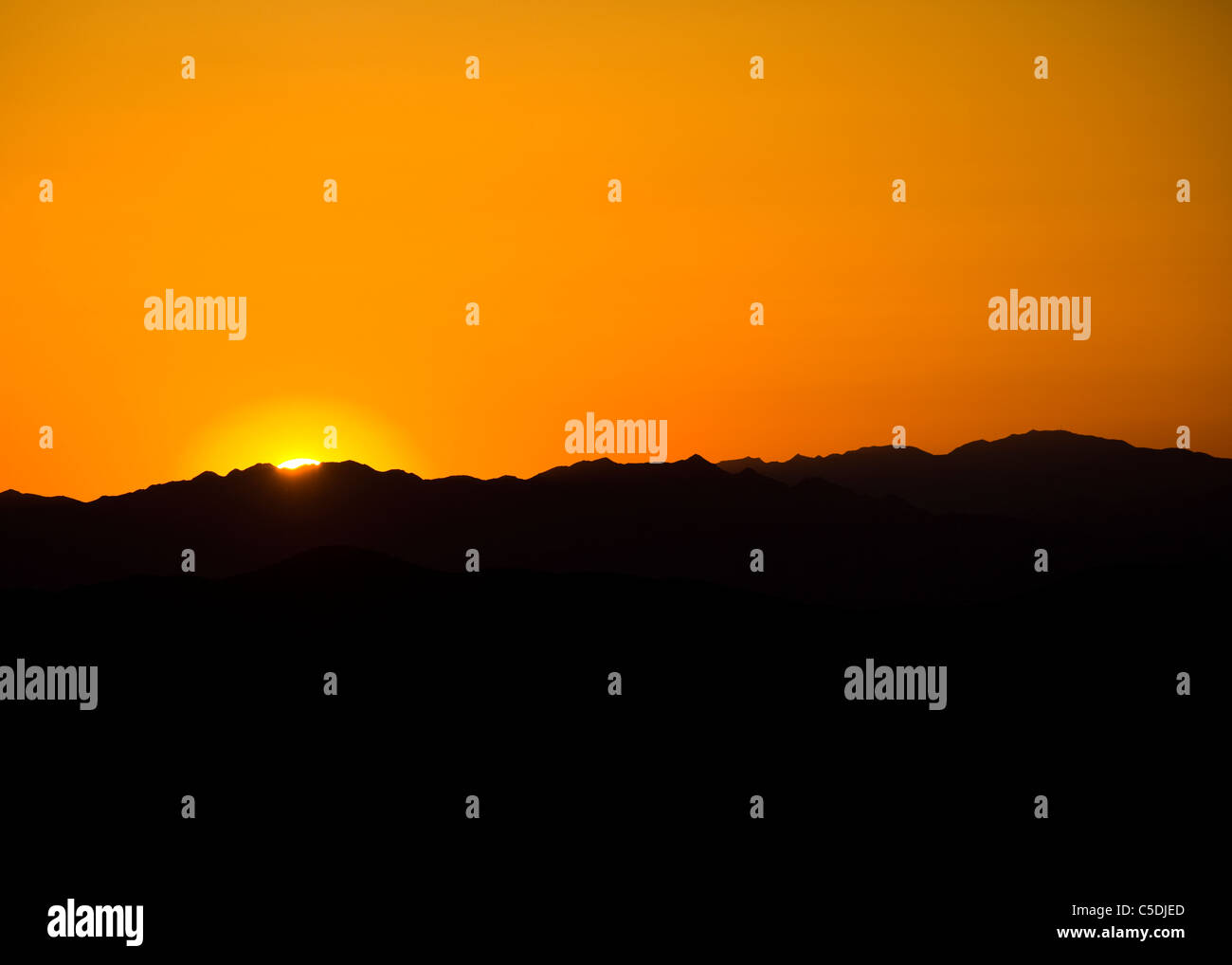Sun sets behind North American Southwest desert mountains - California USA Stock Photo