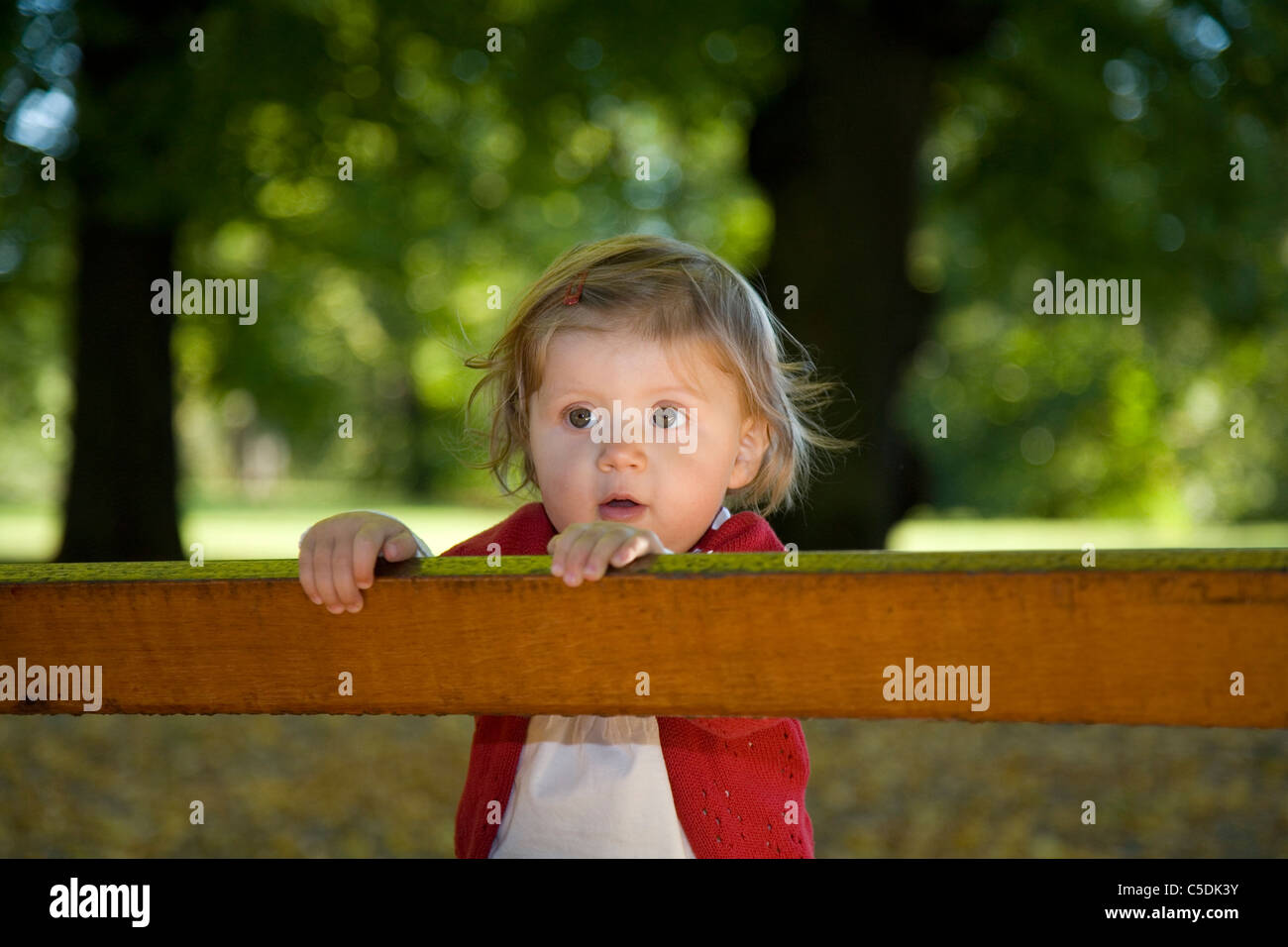 Cute little girl in red sweater with big eyes against the wooden plank Stock Photo