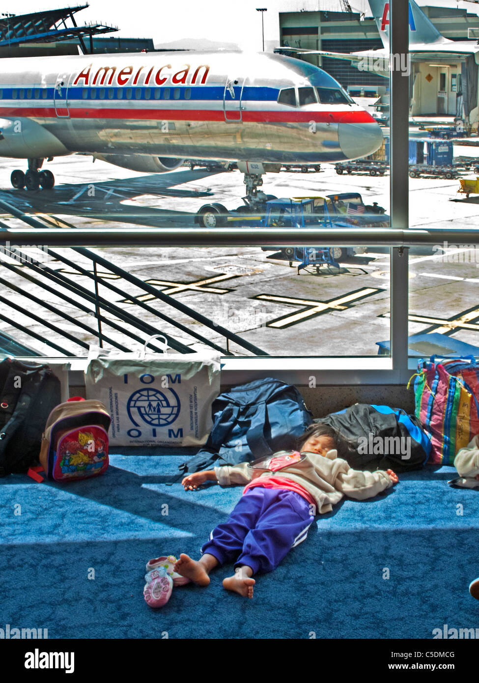 Surrounded by luggage, an Asian child sleeps while waiting for a flight at Los Angeles International Airport, also known as LAX. Stock Photo