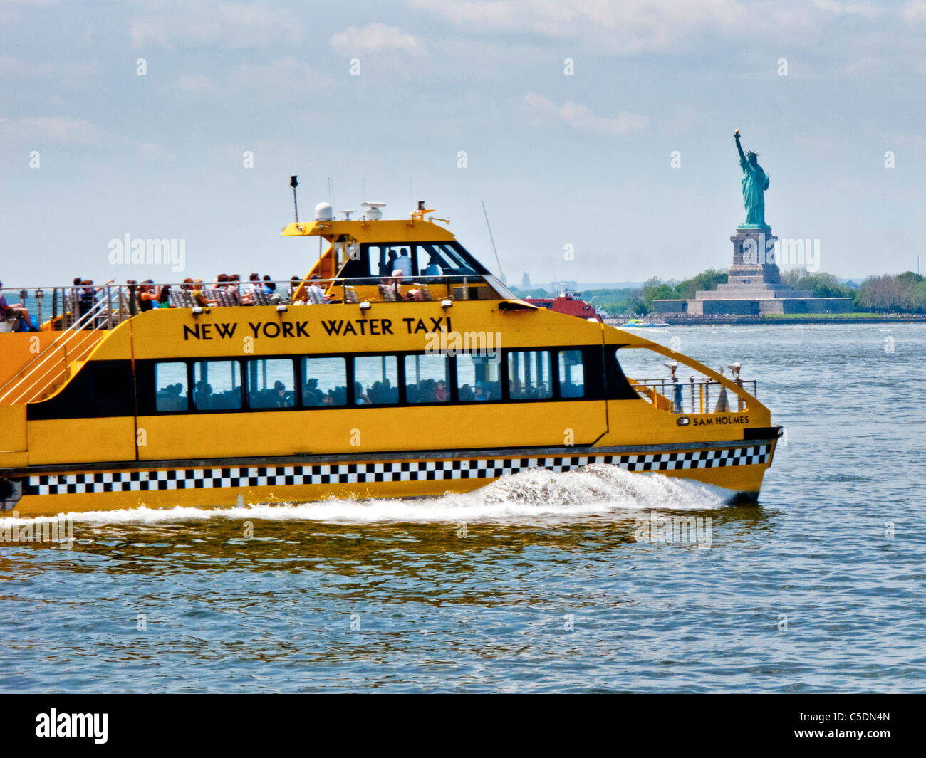 The New York Water Taxi Sam Holmes passes the Statue of Liberty in New York Harbor, and is based in Red Hook, Brooklyn. Stock Photo