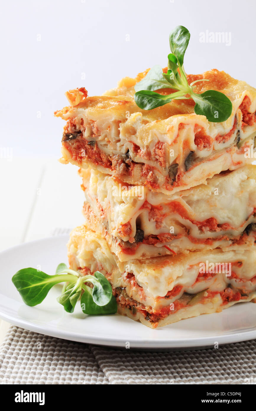 Stack of lasagne garnished with salad greens Stock Photo