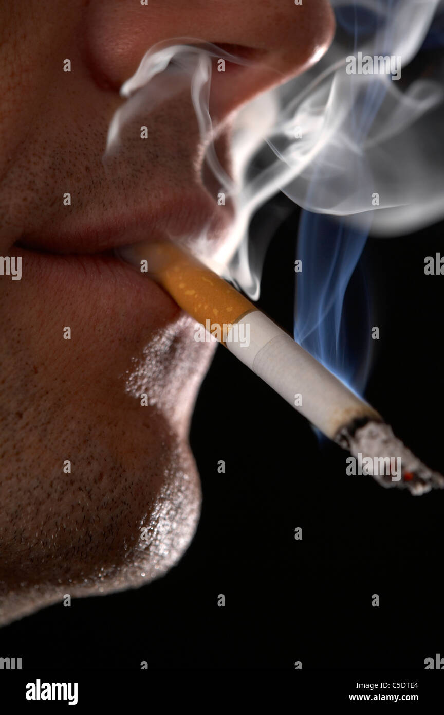 Extreme closeup of a man smoking cigarette against black background