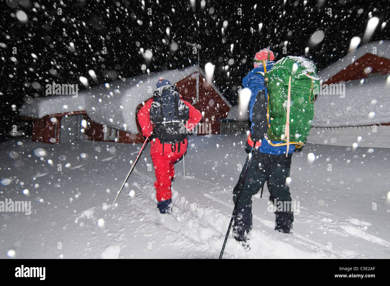 Rear view of two skiers with backpacks on a snowy day in the dark Stock Photo