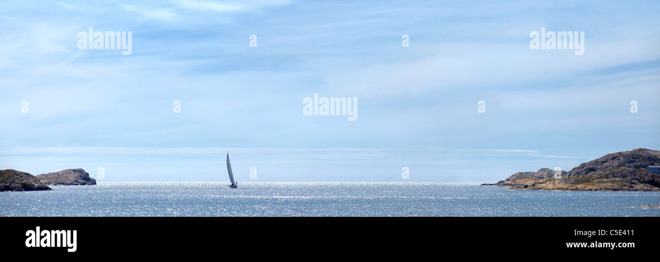 Panoramic shot of peaceful sea with sailboat on the horizon Stock Photo