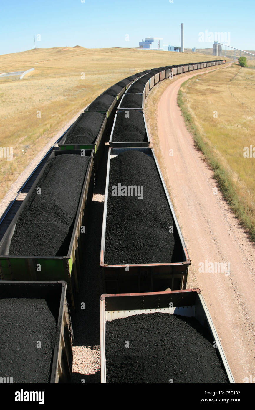 cars from a coal train lead off towards a distant power plant Stock Photo