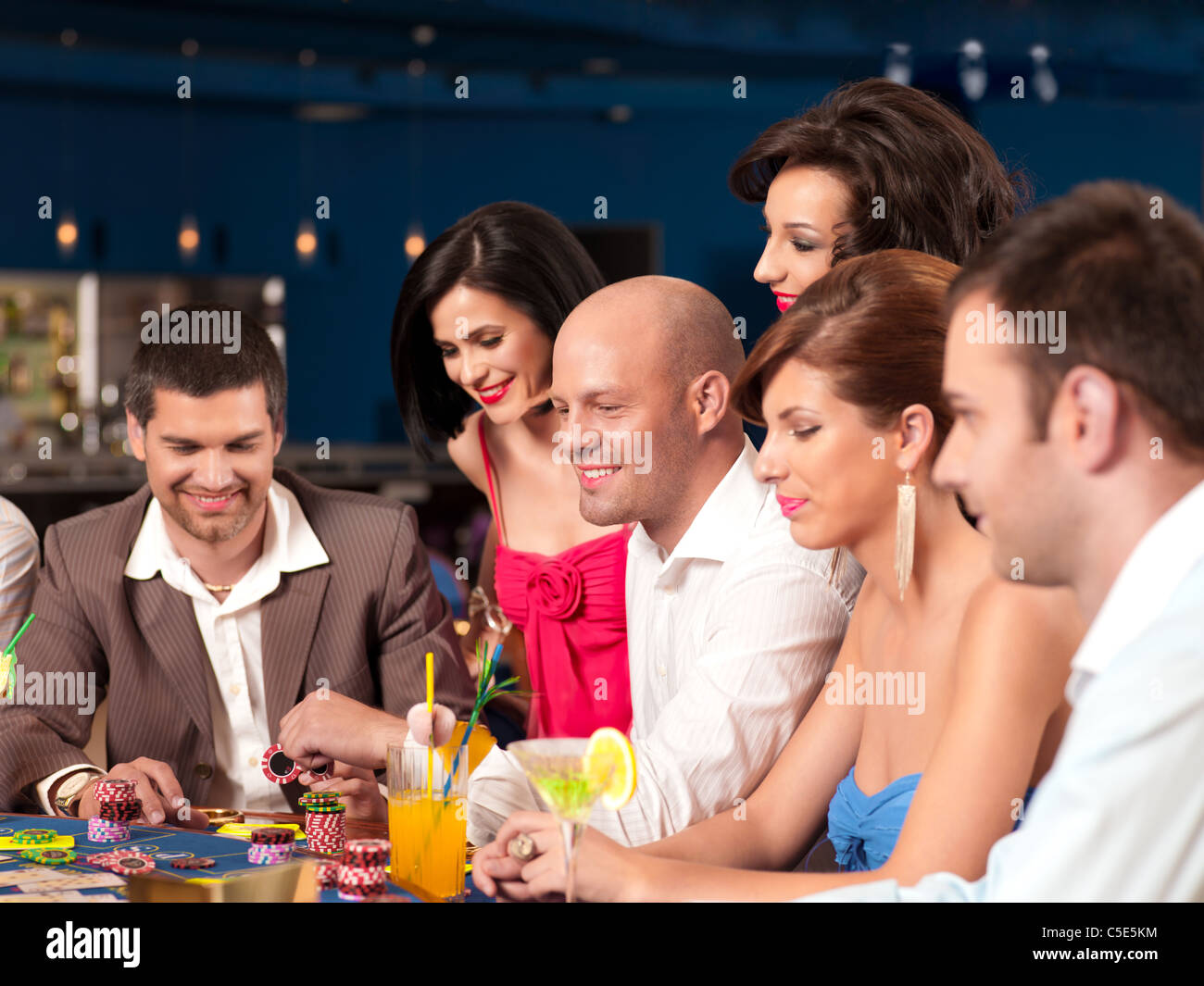 people sitting in a casino poker able, placing their bets Stock Photo
