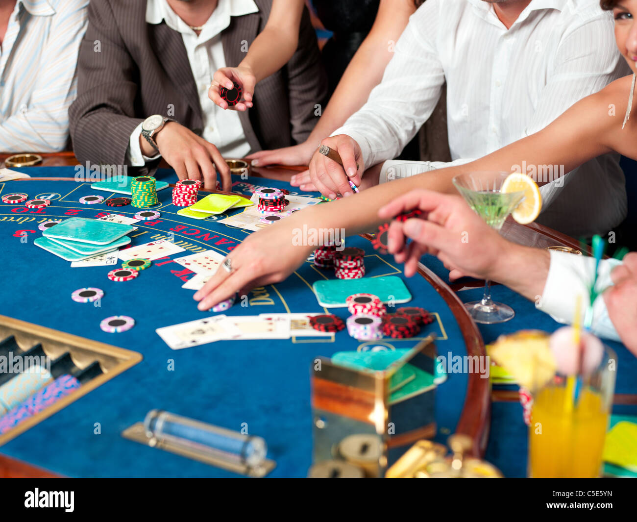 hands on blackjack players with cocktails and casino chips Stock Photo