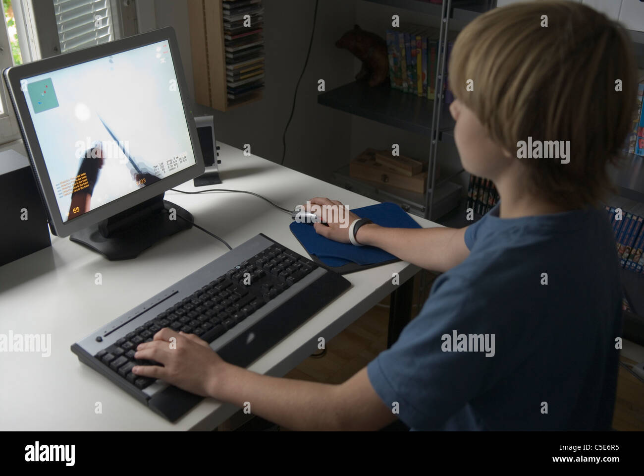Young blond boy playing game on computer at desk Stock Photo