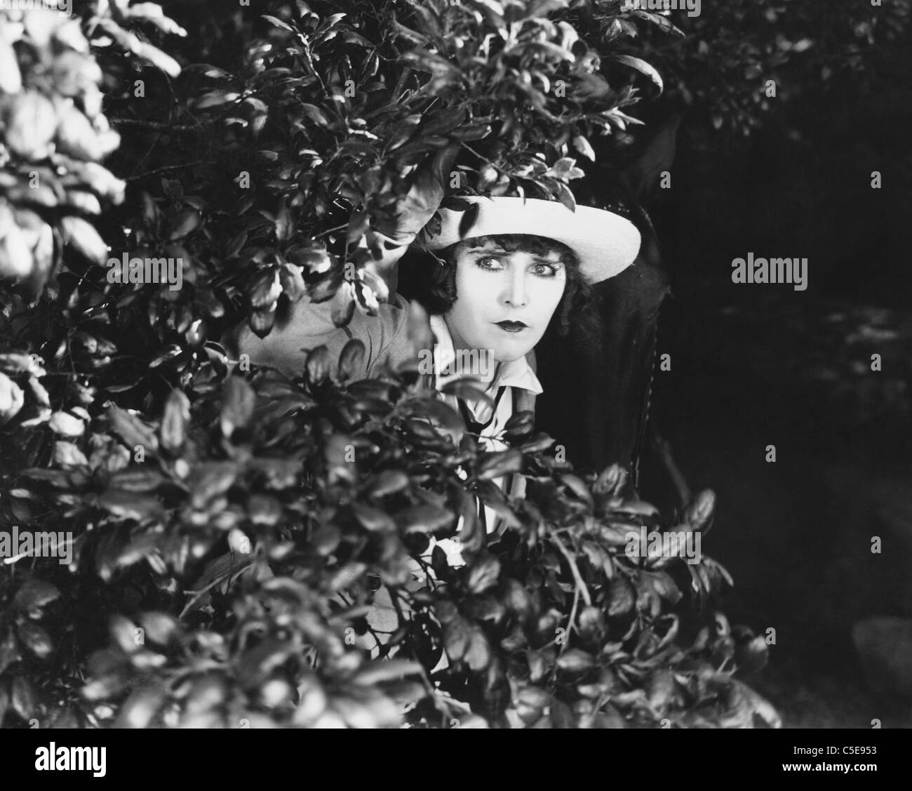 Woman peeking through bushes Stock Photo