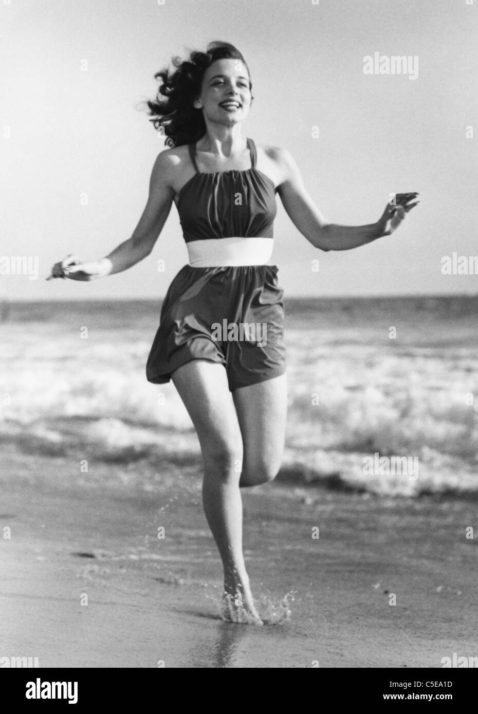 Cheerful young woman running on beach Stock Photo