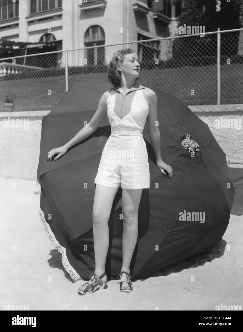 Woman standing in front of beach umbrella on beach Stock Photo