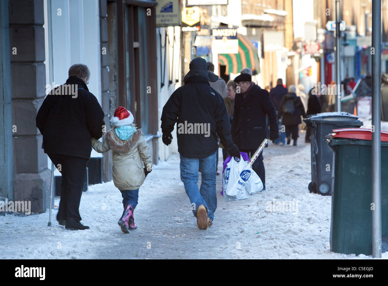 Pedestrians walking cautiously on pavements during winter Stock Photo