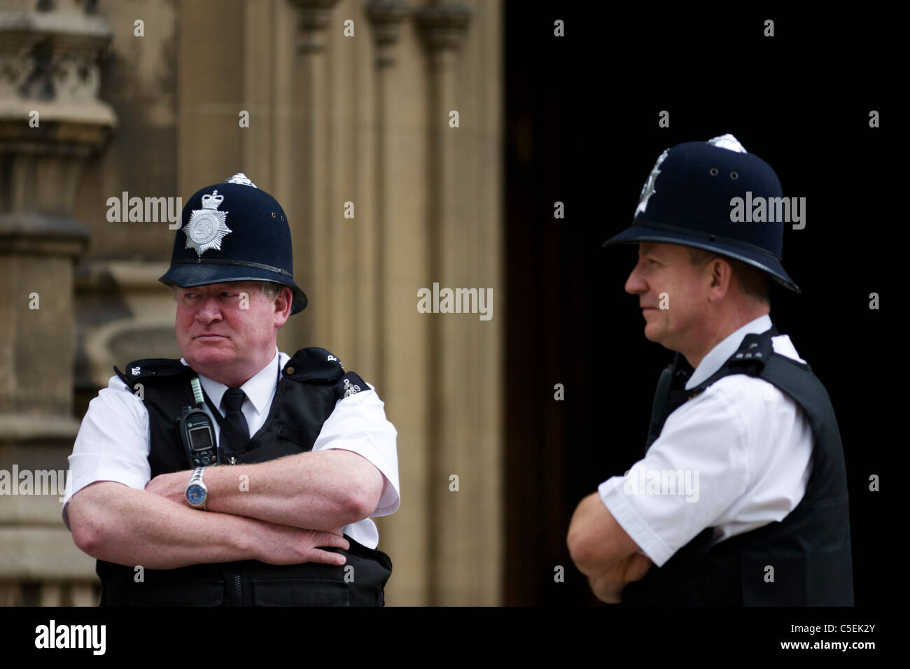 Two Metropolitan police officers talk on duty while guarding Britain's parliament in Westminster, London. Stock Photo