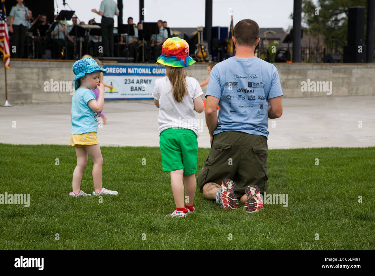 A veteran and his two children listen to the US Army Band at an outdoor concert in Bend, Oregon Stock Photo