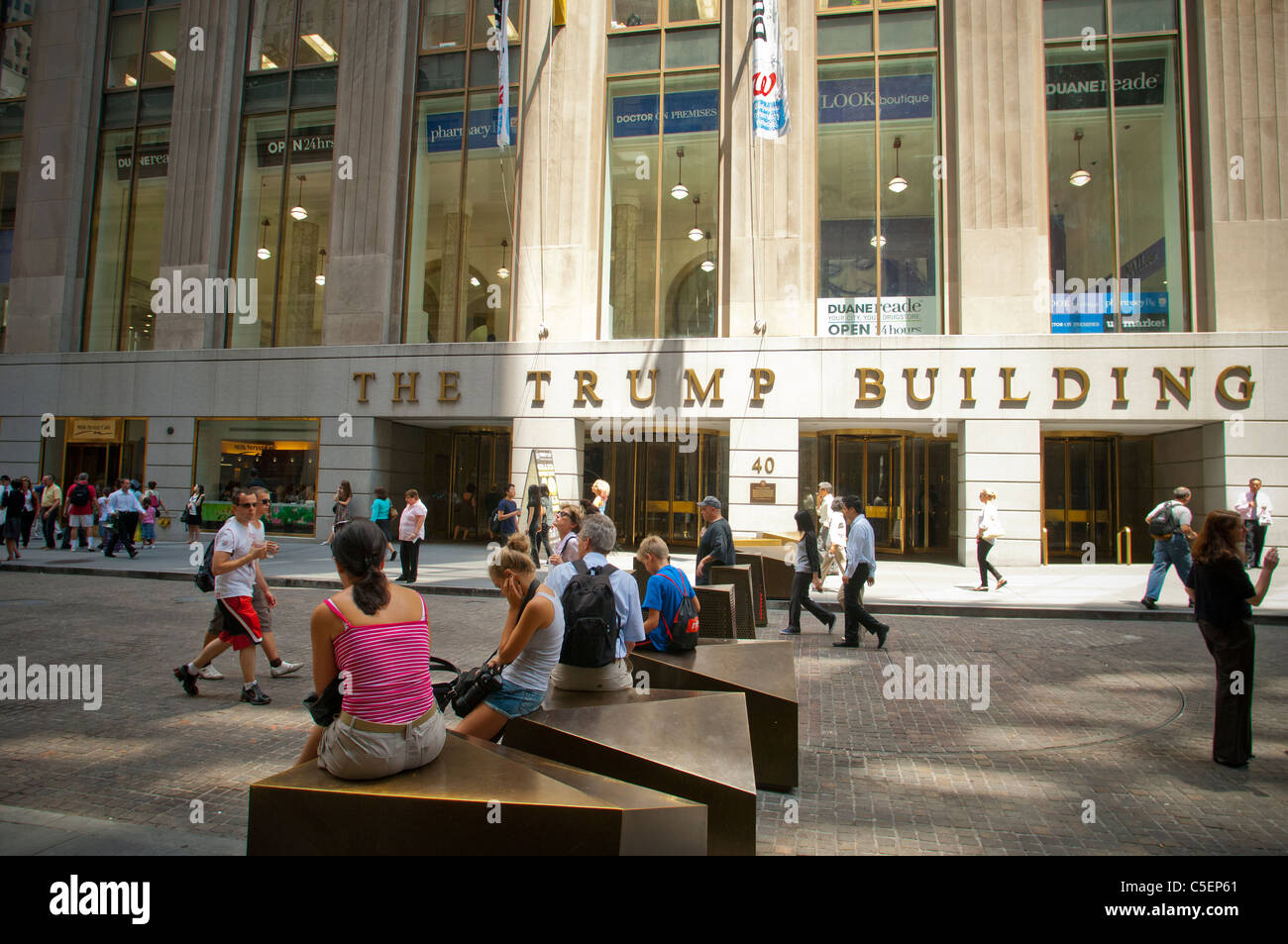 Tourists rest on the security bollards on Wall Street in Lower Manhattan in New York Stock Photo