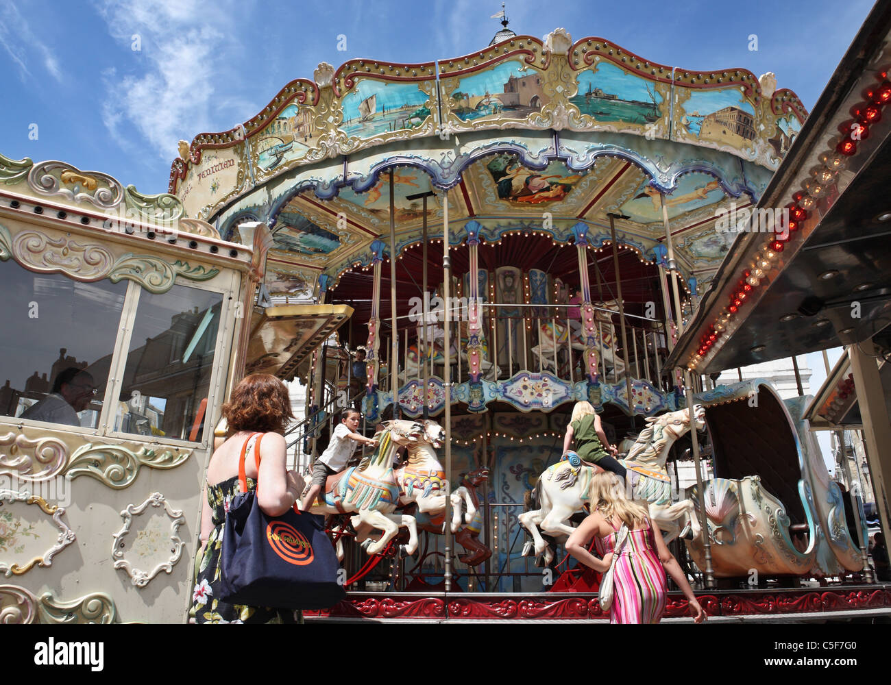 Mothers watching their children ride a carousel roundabout within the town of Auray, Brittany, France Stock Photo