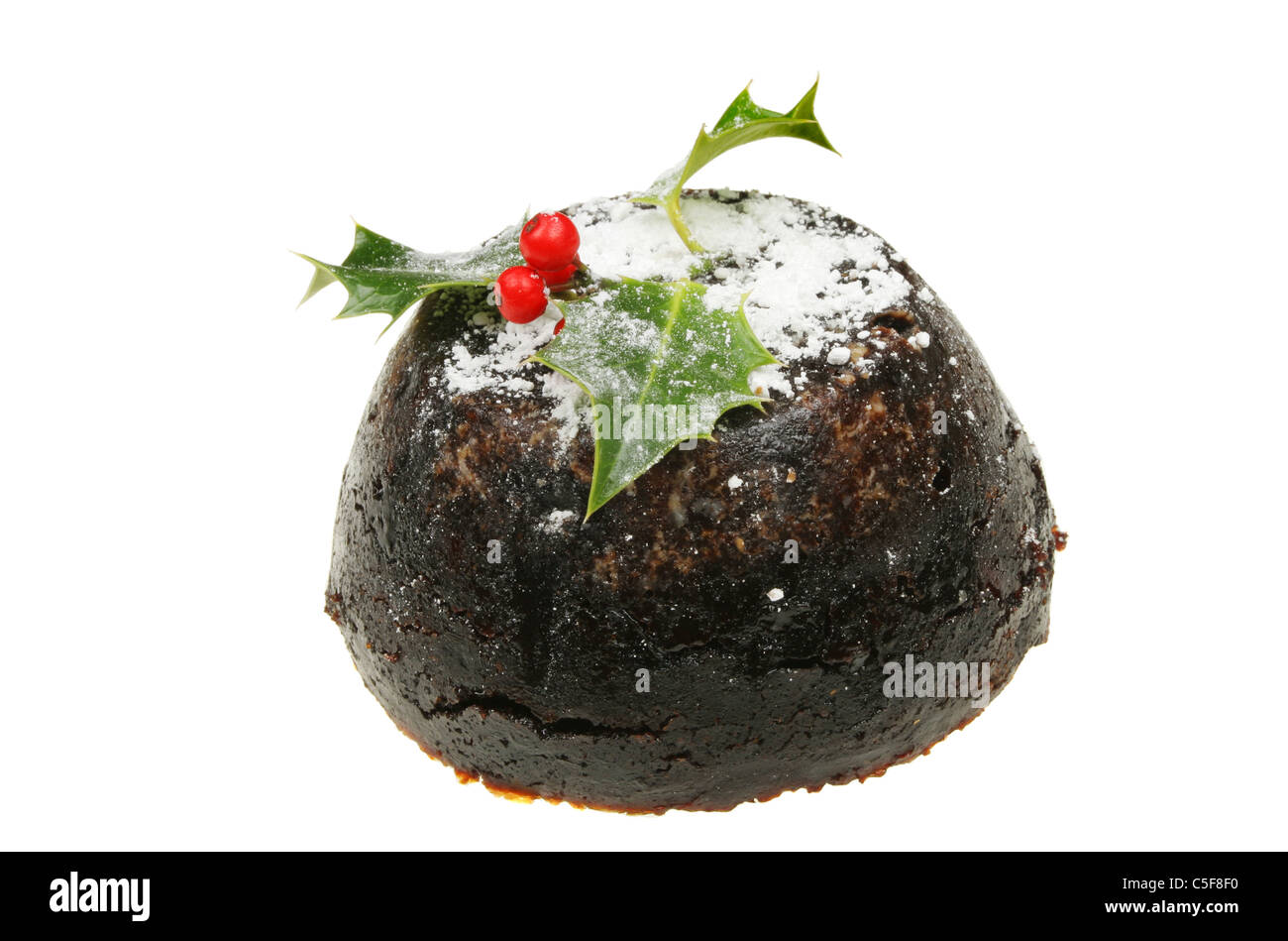 Christmas pudding dusted with sugar and decorated with a holly sprig Stock Photo