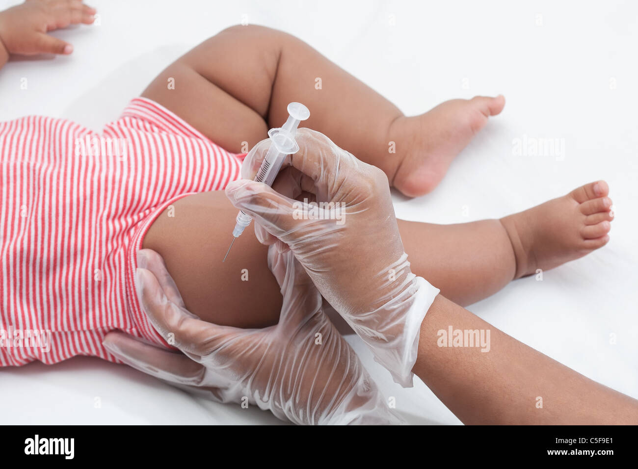 Nurse giving a baby a vaccine in the leg, latex free gloves Stock Photo