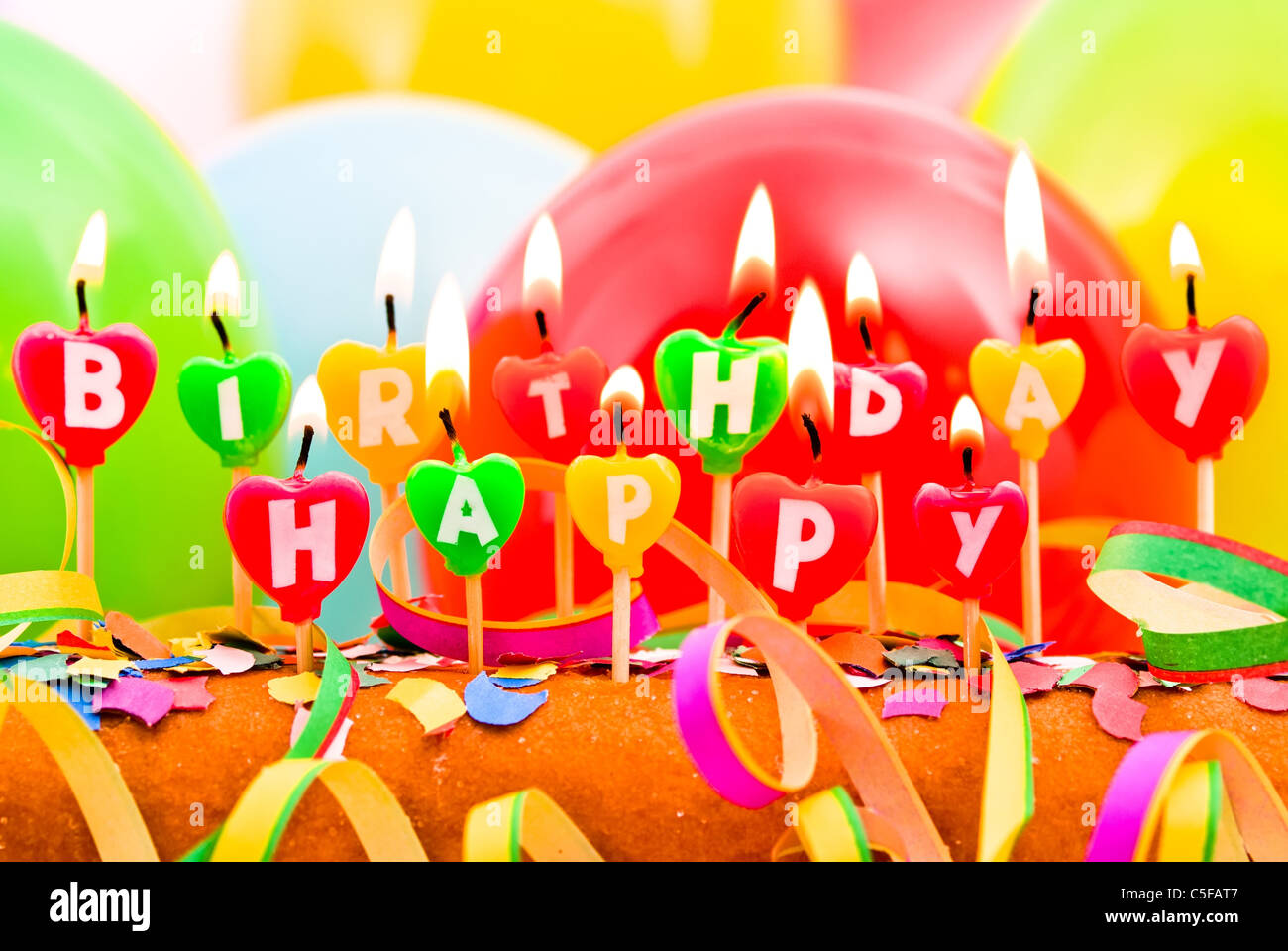 burning happy Birthday candles with balloons and confetti Stock Photo