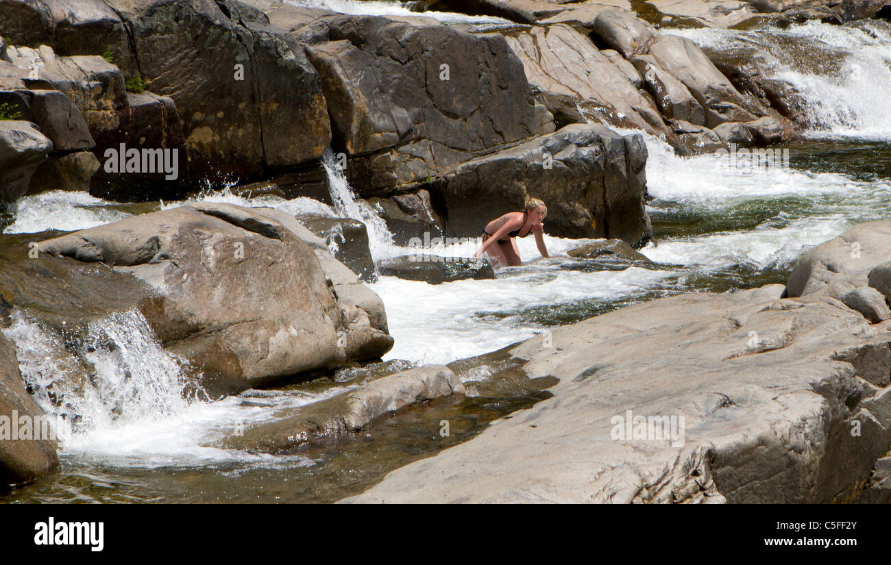 Blond girl in a black bikini in the rapids of a river Stock Photo