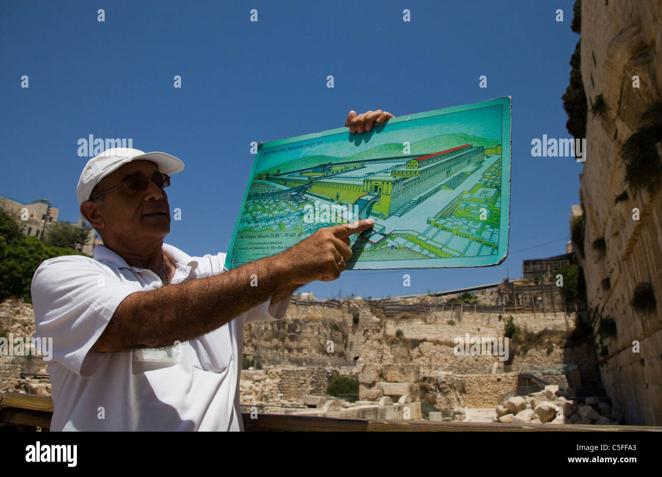 A guide tour holds a map depicting the ancient Jewish temple as he stands next to the renovation site of Mughrabi Bridge Old city Jerusalem Israel Stock Photo