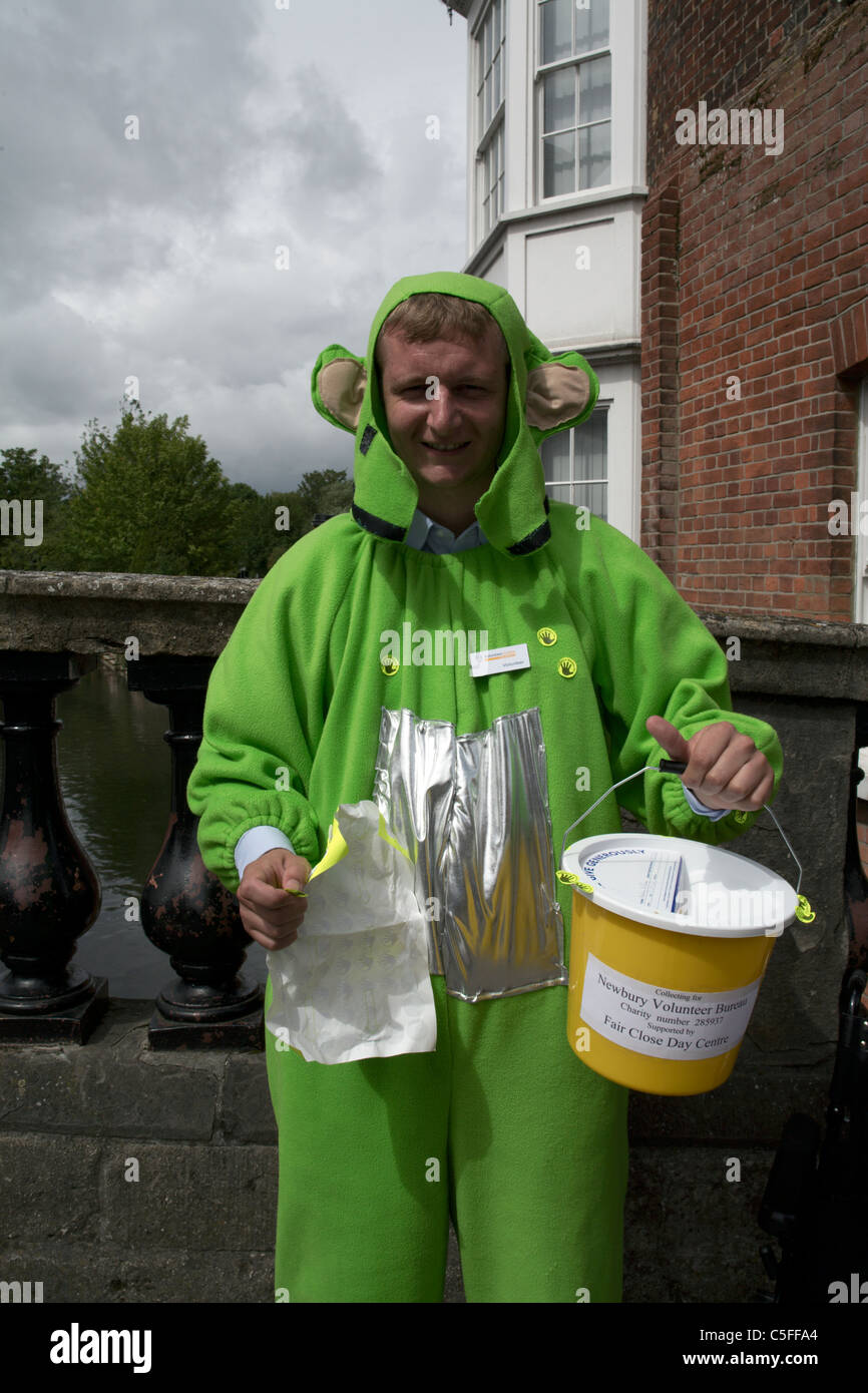 Charity collector man on the town bridge in Newbury Berkshire England dressed in green animal suit holding up collecting bucket Stock Photo