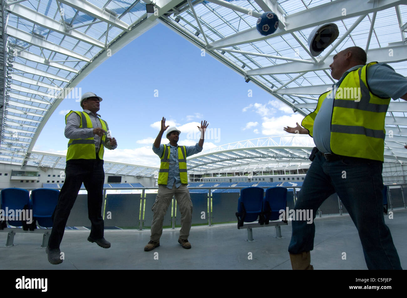 Three builders having a kickabout as work nears completion on the new AMEX stadium, home of Brighton and Hove Albion Football Club from 2011. Stock Photo