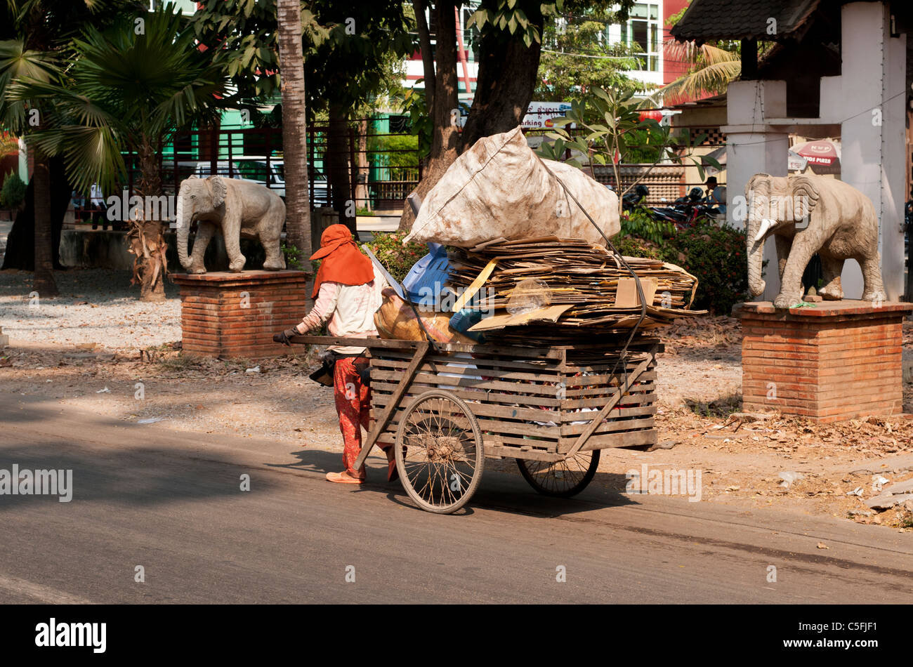 Recycled materials scavenger pulling a handcart piled with cardboard and plastic waste, Siem Reap, Cambodia Stock Photo