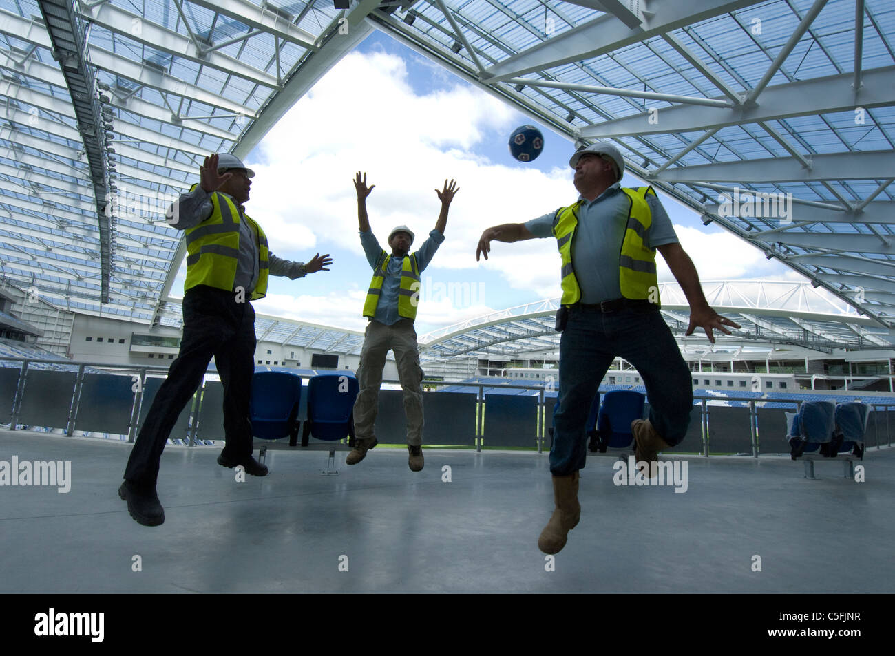 Three builders having a kickabout as work nears completion on the new AMEX stadium, home of Brighton and Hove Albion from 2011. Stock Photo