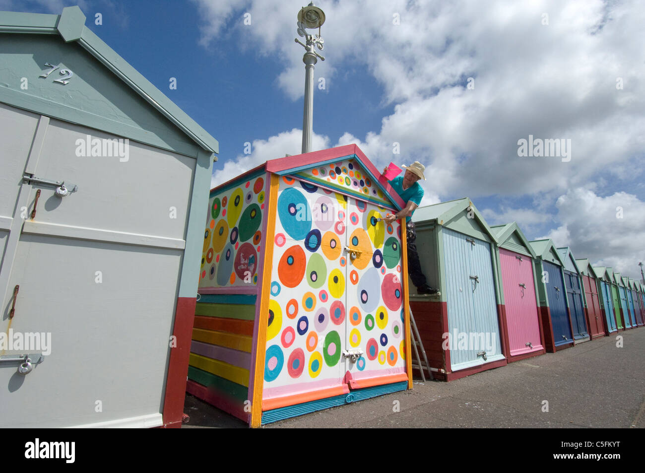 Odd one out. A rebel beach hut stands out from a uniformly painted row. Stock Photo