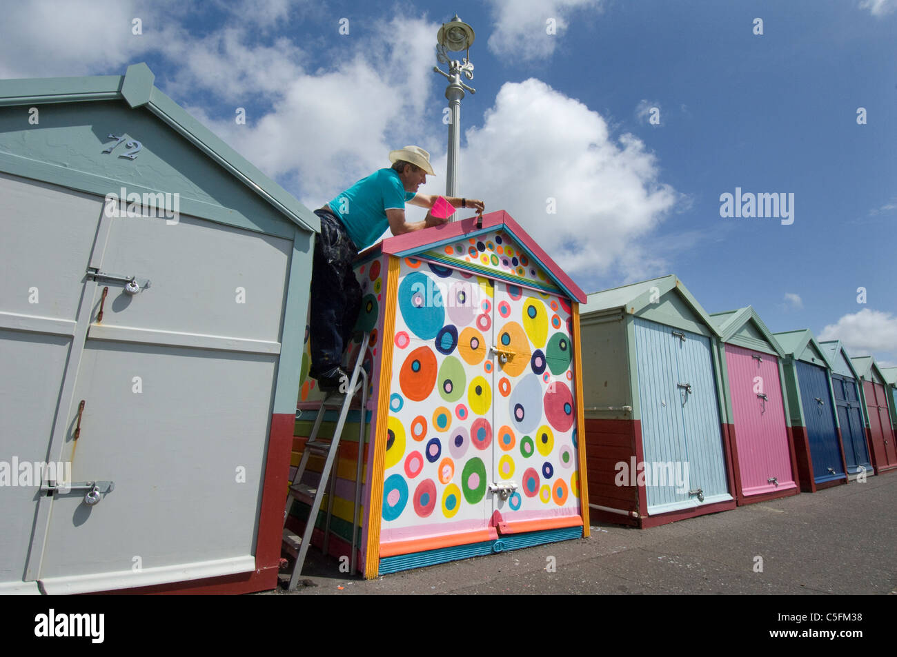 Man painting a beach hut in non-regulation colours Stock Photo