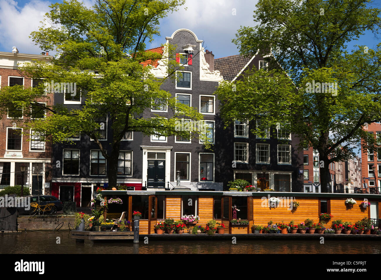 Traditional house boat on the canal at Princen Gracht, with traditional houses behind, Amsterdam Stock Photo
