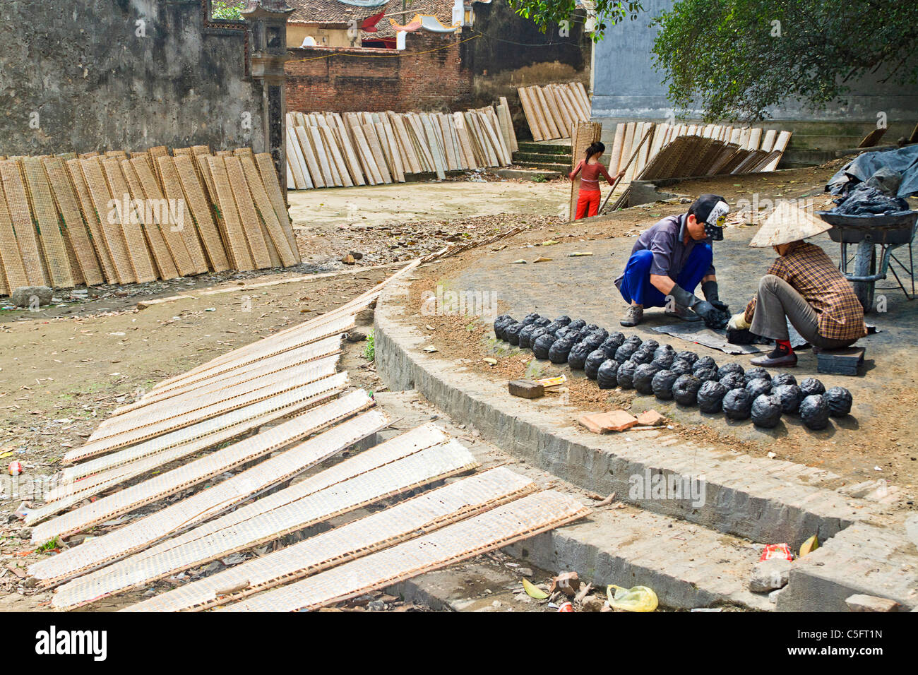 Rice paper (used in cooking) dries on racks while workers make 'bee hive' coal in Tho Ha village, on a small island near Hanoi Stock Photo