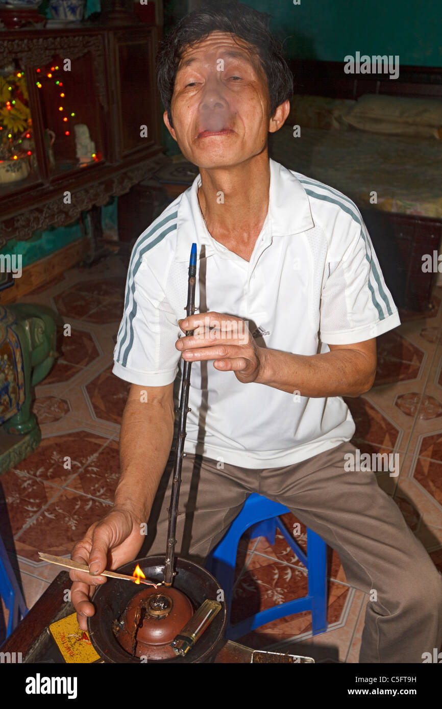 Viet Trinh Quang, 53, of the Kinh tribe, smokes using a smoking bowl (Thuoc  Lao) in his home in Tho Ha village, Vietnam Stock Photo